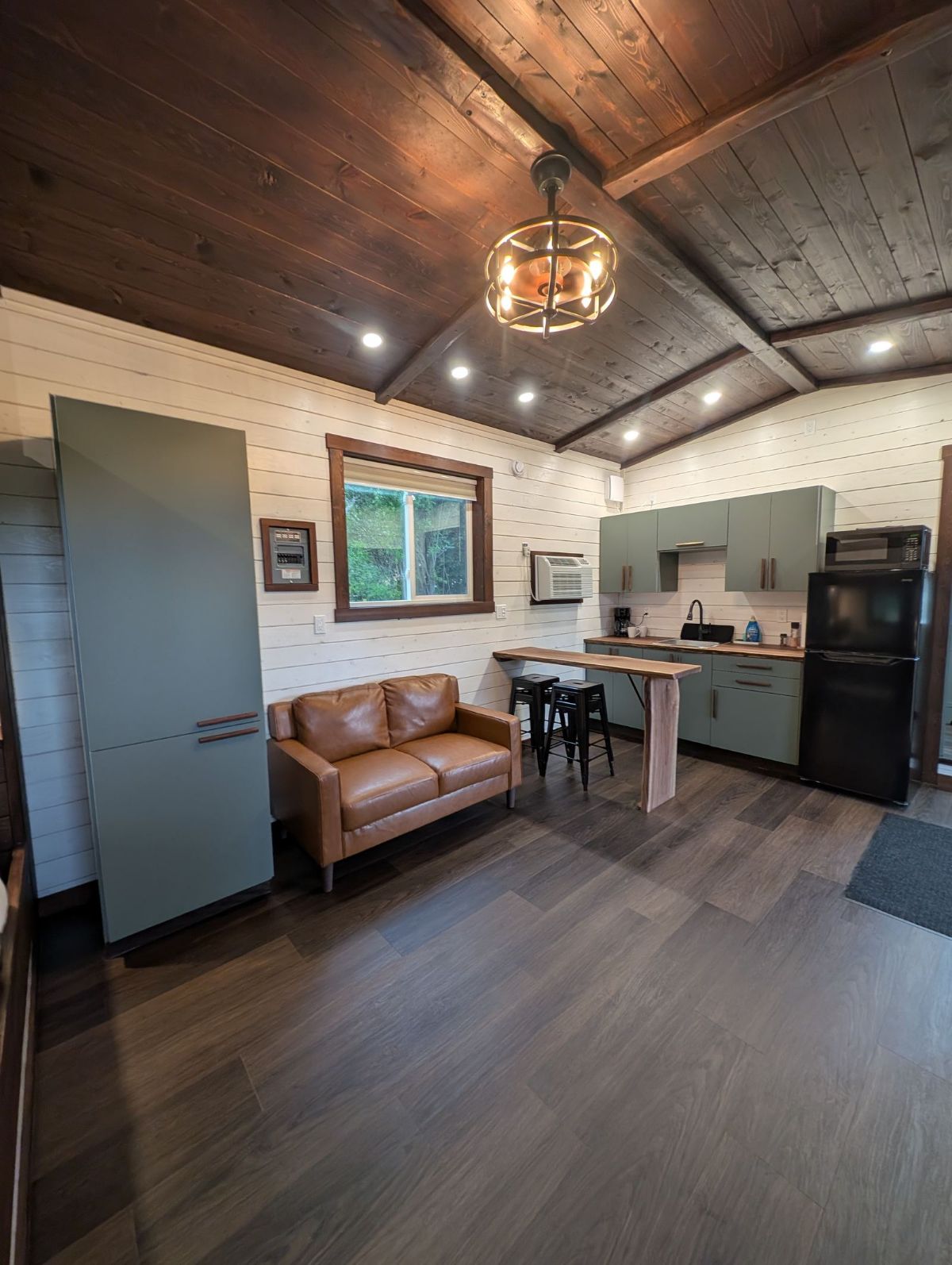 Inside a Sage Cabin — living area, kitchenette, and wood-beamed ceiling